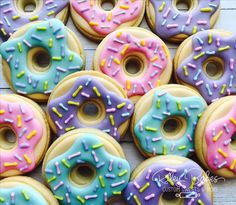 many donuts with different colored frosting and sprinkles