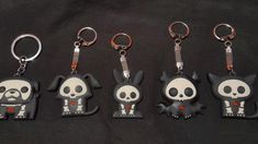 four keychains with different designs on them sitting next to each other in front of a black background