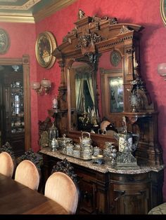 an old fashioned dining room with red walls and antique furniture, including a large mirror