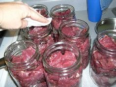 several jars filled with red meat sitting on top of a stove