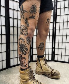 the legs and ankles of a man with tattoos on his body, wearing combat boots