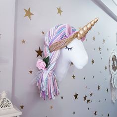 a unicorn head mounted to the side of a wall with gold stars and pink flowers