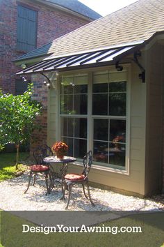 an outdoor patio with table and chairs next to a brick building that has a metal awning over it