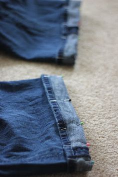 two pairs of blue jeans are laying on the floor next to each other and one pair is missing