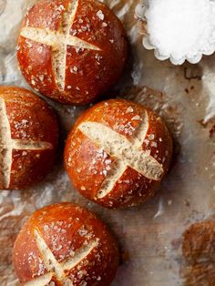 three hot cross buns sitting on top of a piece of tin foil covered in powdered sugar