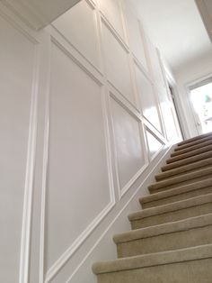 the stairs are lined with beige carpet and white paneling on either side of the door