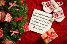 a christmas tree with presents and decorations around it on a red blanket next to a white sign that says merry christmas