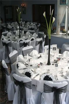 the table is set with white and black linens, silver napkins, and flowers