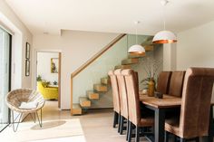 a dining room table with chairs and a staircase in the backround behind it