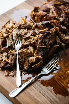 a wooden cutting board topped with meat and a fork