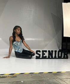 a woman sitting on the ground in front of a sign