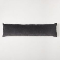 a black rectangular pillow sitting on top of a white wall