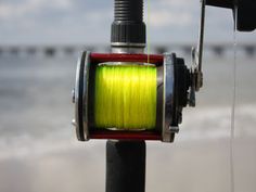 a fishing rod with a spool of yellow thread attached to it next to the ocean