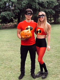 a man and woman in halloween costumes posing for a photo with a pumpkin on their chest