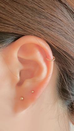 a woman's ear is shown with two piercings