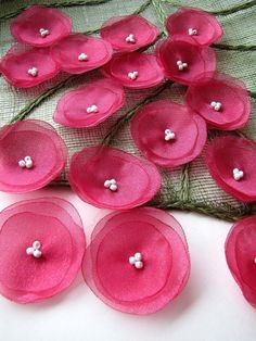 some pink flowers are sitting on a white table cloth and there is no image here to provide a caption for