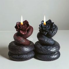 two candles are placed on top of each other with black and red snakes around them