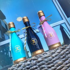 three different colored bottles sitting on top of a rope in front of a store window