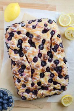 blueberries and lemons are sitting on wax paper next to some sliced lemons