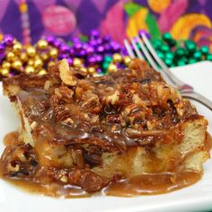 a white plate topped with cake covered in caramel and pecans next to a fork