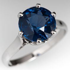 a blue diamond ring with silver accents on the sides and an oval cut stone in the middle