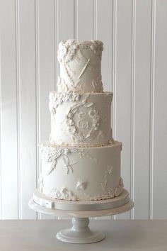 a three tiered white wedding cake sitting on top of a table