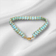 a bracelet with blue beads and gold clasps on a white satin background, close up