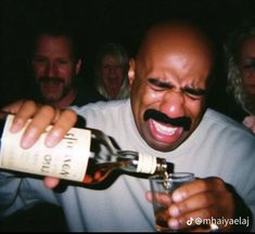 a man with a moustache on his face holding a bottle of alcohol in front of him