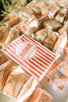 an orange and white striped paper bag sitting on top of a table filled with candy