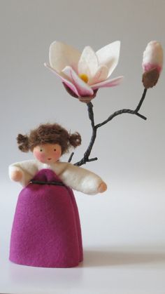 a small doll sitting on top of a purple object with flowers in it's hair