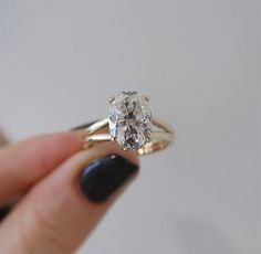 a close up of a person's hand holding a ring with a diamond in it