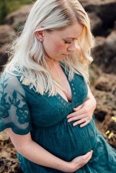 a pregnant woman in a green dress is posing for the camera while holding her stomach