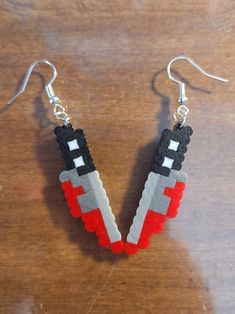 a pair of earrings made out of legos sitting on top of a wooden table