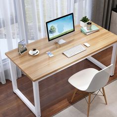 a wooden desk with a computer monitor and keyboard sitting on top of it next to a white chair