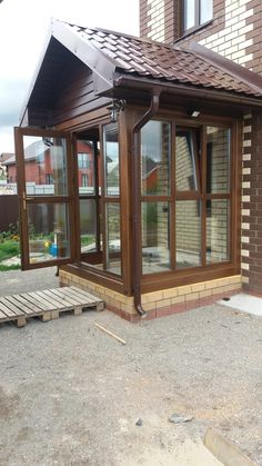 a small house with an attached patio and covered in wood shinnings on the roof