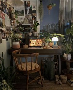 a desk with plants and pictures on the wall above it, along with a chair