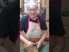 an older woman is preparing food in the kitchen while wearing an apron and smiling at the camera