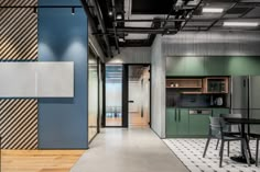 an office with blue and green walls, wooden flooring and black chairs in the middle