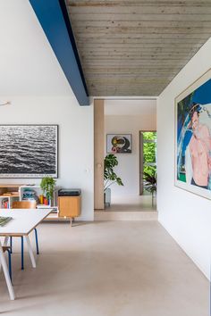 a living room filled with furniture and paintings on the wall next to a dining table