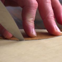 a person cutting paper with a pair of scissors on top of the edge of a piece of wood