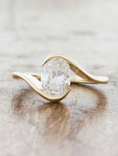 a close up of a ring with a diamond on the top and bottom, sitting on a wooden surface