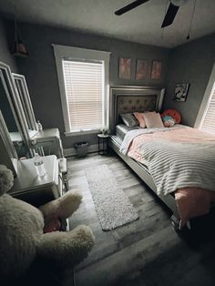 a bed room with a neatly made bed and a teddy bear sitting on the floor