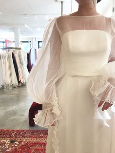 a woman in a white dress is standing on a red rug and wearing a veil