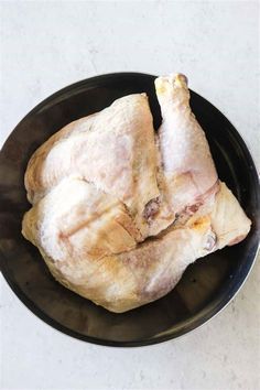 raw chicken in a black bowl on a white table