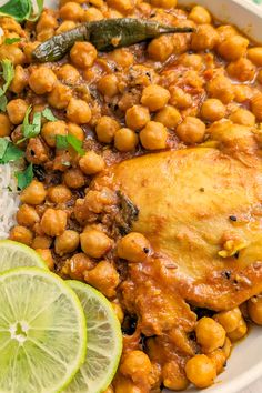 a white bowl filled with chickpeas and rice next to a lime wedge on the side