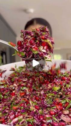 a bowl filled with red cabbage and pomegranate being spooned into it