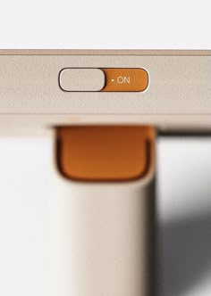 an orange button is on the side of a white table with a silver frame and metal legs