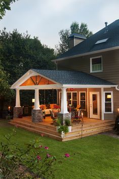 a house with a covered patio and deck in the evening light, surrounded by lush green grass