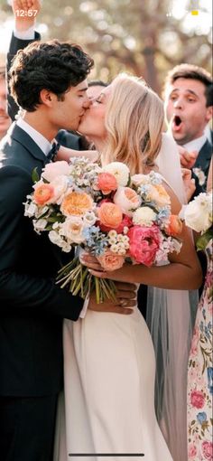 a bride and groom kissing in front of their wedding party