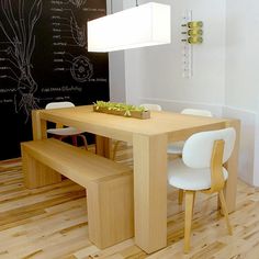 a dining room table with white chairs and a light on the wall above it that is attached to a chalkboard